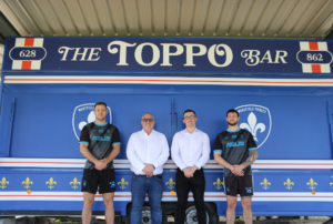 Jon Newall, CEO of Prosura, Callum Topliss, Commercial Account Executive, and two Wakefield Trinity Rugby League players pictured in front of 'The Toppo Bar'.