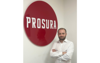 An image of Prosura's newest recruit, Daniel Shelford, stood in front of the Prosura sign in the office.