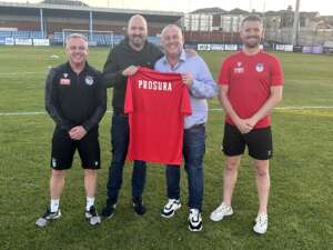 Jon Newall is pictured on the pitch at Ossett United Football Club alongside team representatives 