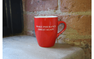 An image of a red mug against an exposed brick background that has the wording "make insurance great again" on the front.