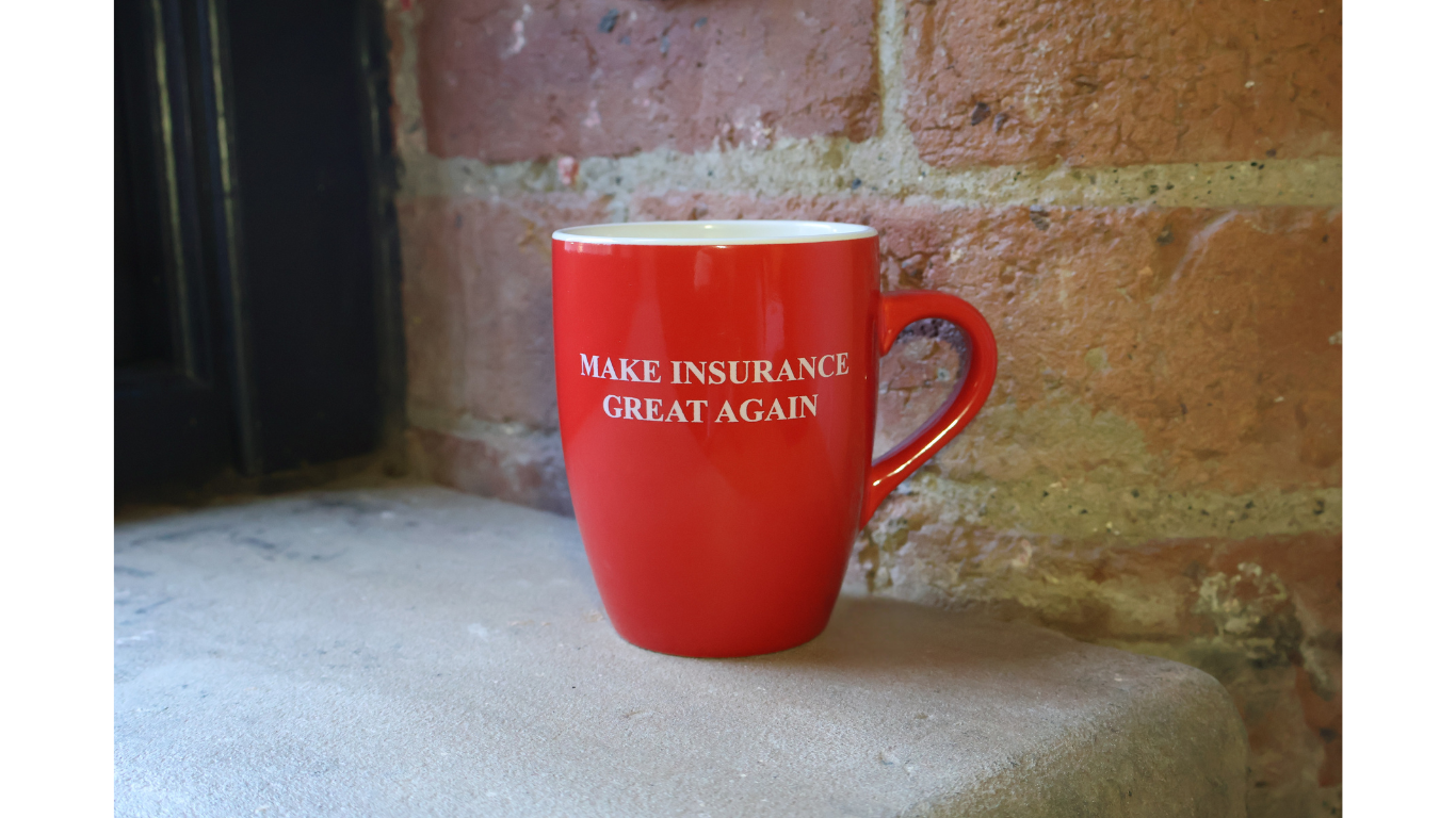 An image of a red mug against an exposed brick background that has the wording "make insurance great again" on the front.